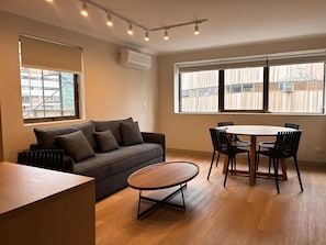 A modern living room with a sofa, a round coffee table, and a dining table with chairs. - RQ Costanera Apartments (Santiago)