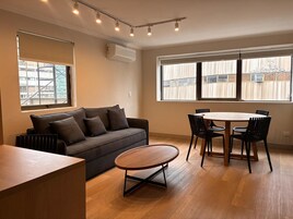 Una sala moderna con un sofá, una mesa de centro redonda y una mesa de comedor con sillas.