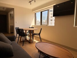 Una sala de estar moderna con comedor, un sofá, una mesa y sillas.