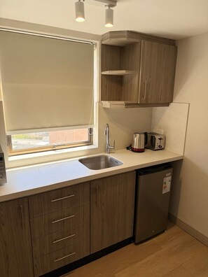 A compact kitchen with a window, a sink, a toaster, and a dishwasher.