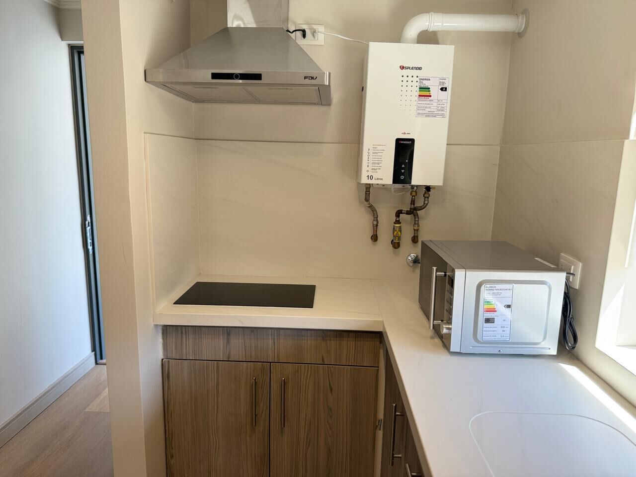 A modern kitchen with a built-in stove, a water heater, and a microwave.