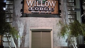 The exterior of Willow Lodge with a prominent sign, a registration sign, and a window with blinds. - Willow Lodge (Murrells Inlet)