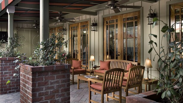 An outdoor patio area with brick planters, wooden furniture, and a ceiling fan. - Willow Lodge (Murrells Inlet)