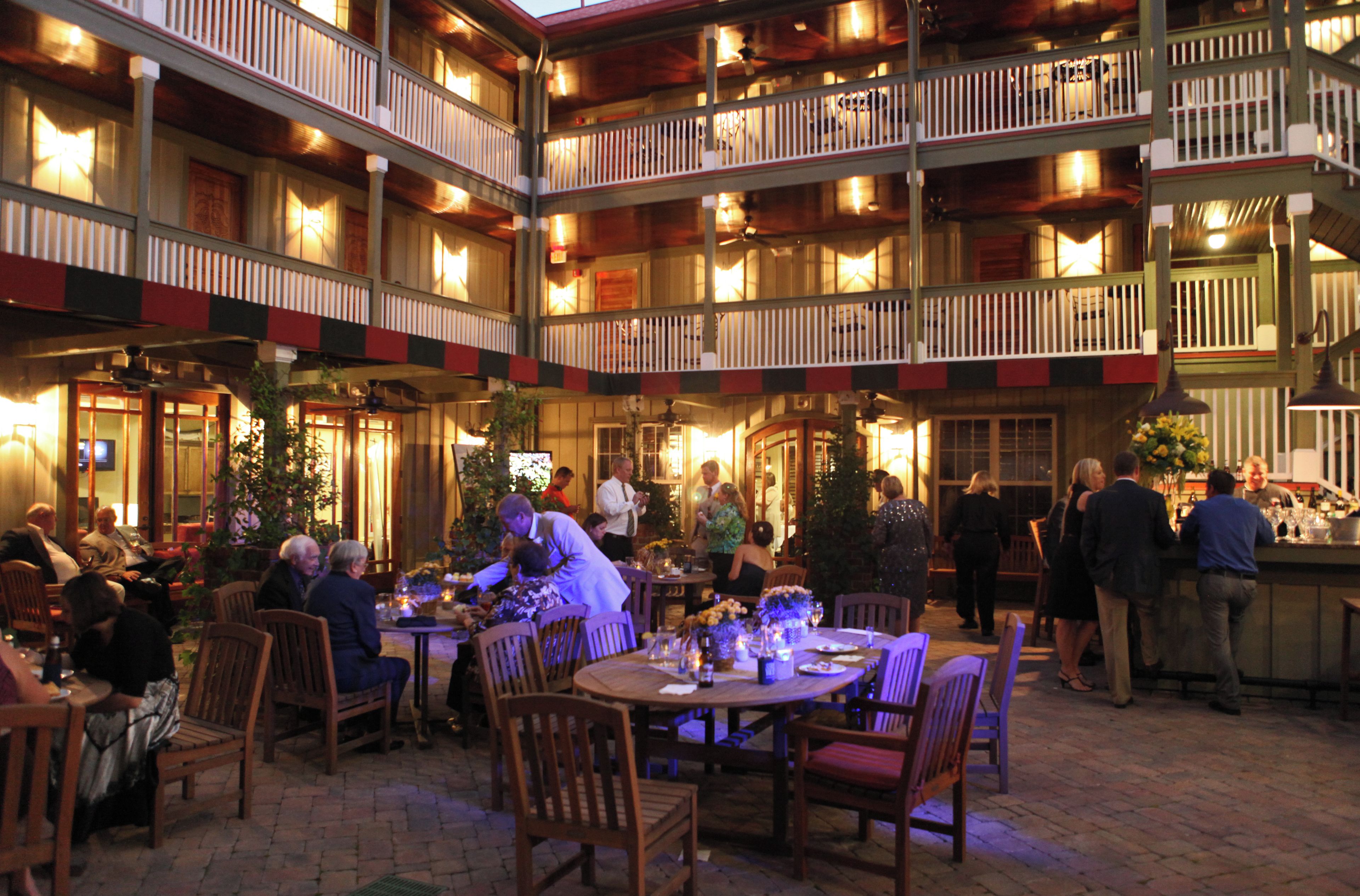 A multi-level outdoor dining area with tables and chairs, surrounded by balconies with railings.