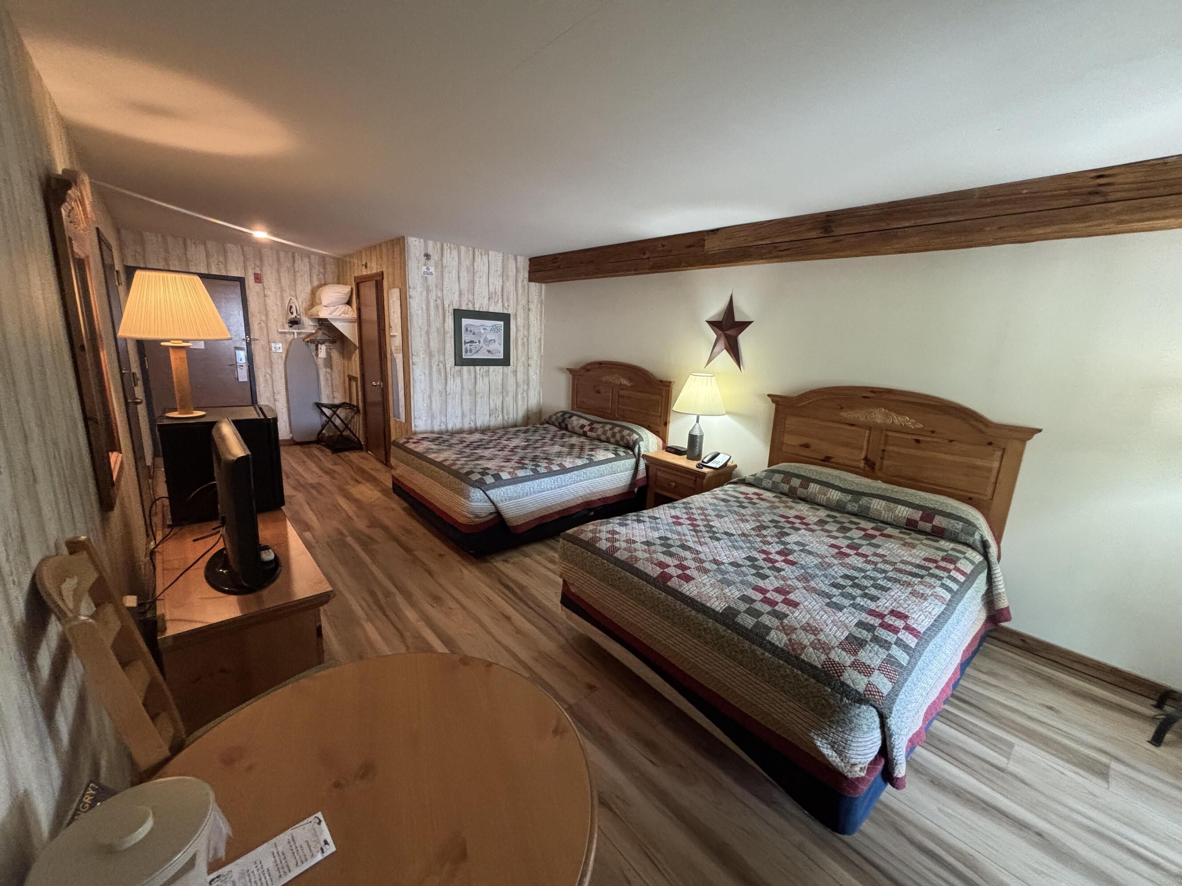 A hotel room with two beds, a round table, a lamp, and a star decoration on the wall.