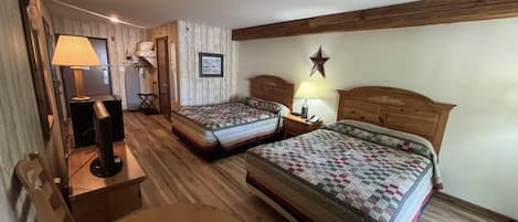 A hotel room with two beds, a round table, a lamp, and a star decoration on the wall.