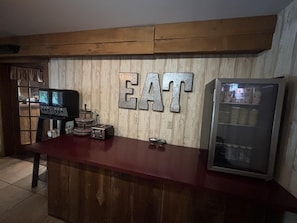 Una barra de madera con un letrero grande que dice 'EAT', una radio antigua y un refrigerador.