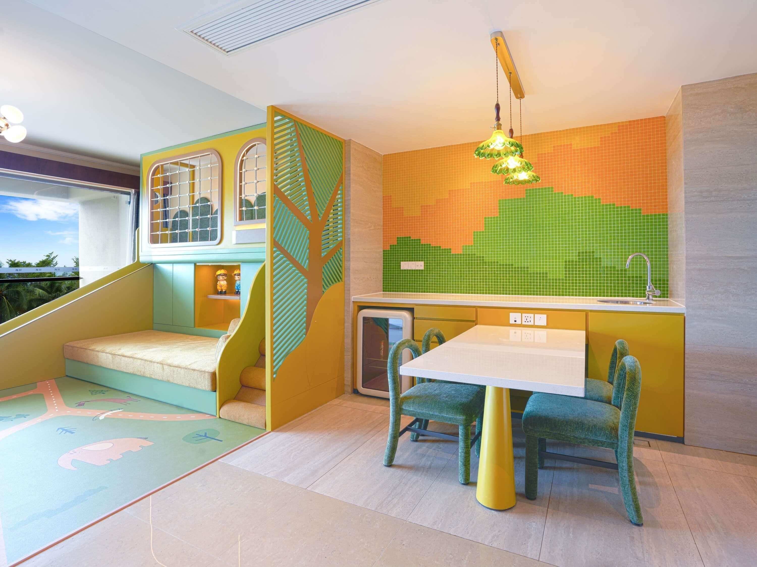 Ein Spielbereich für Kinder mit Rutsche, Krabbeldecke und Tisch mit Stühlen.