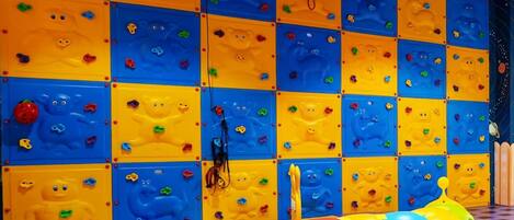 Un mur d’escalade avec des prises de couleurs vives et un sol rembourré.