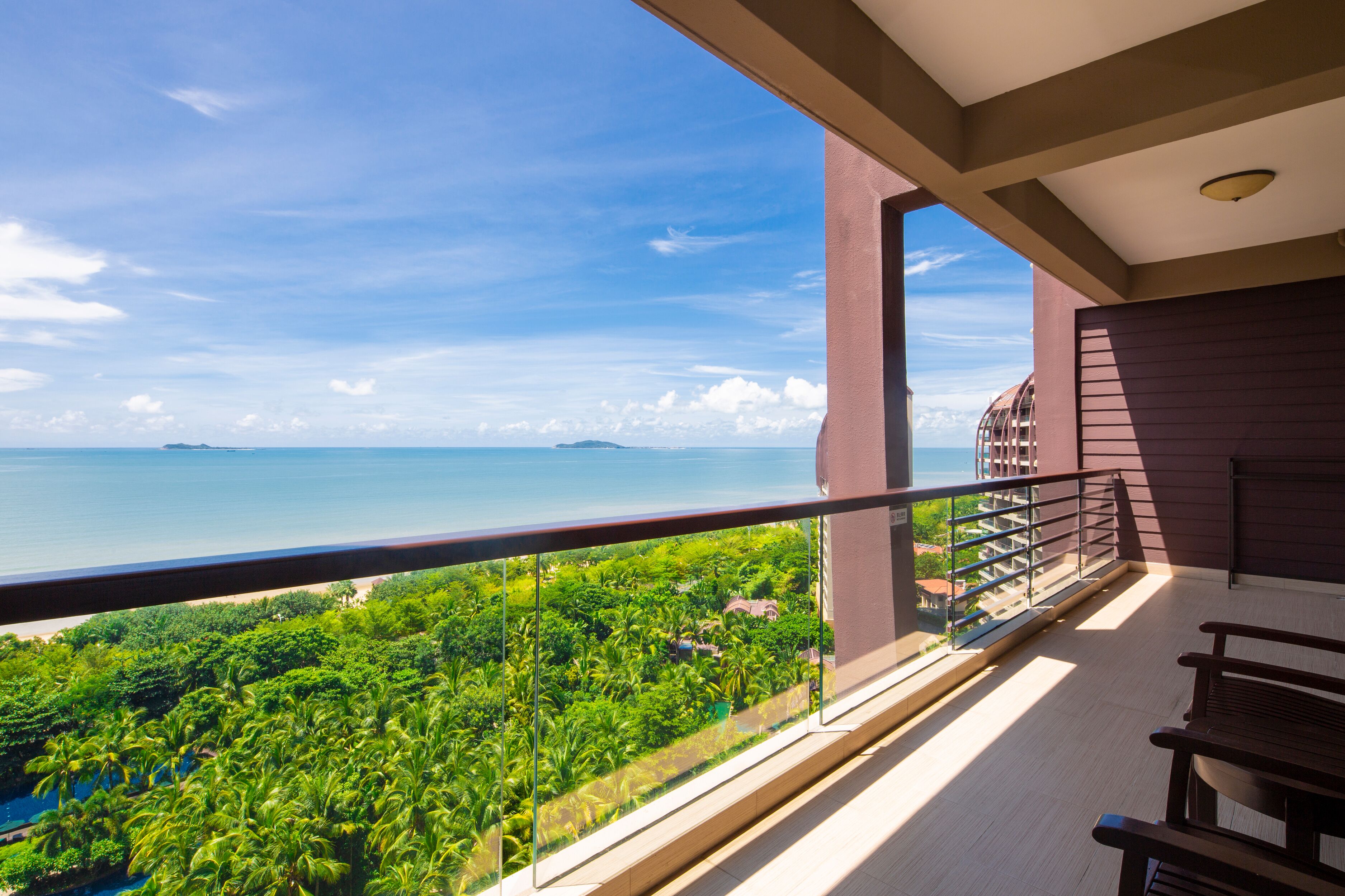 A balcony with a view of the sea and greenery.