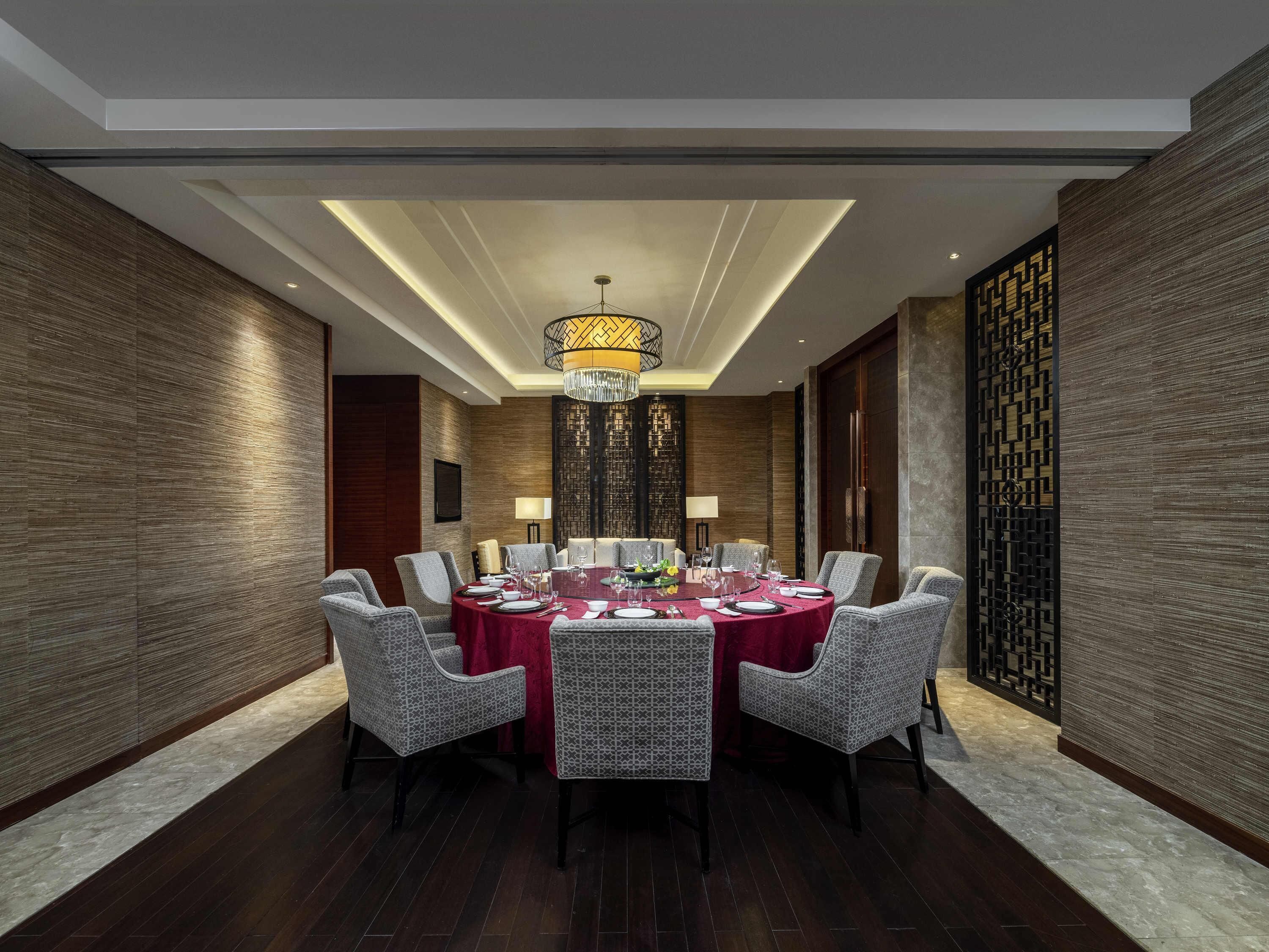 A modern dining room with a round table set for eight, surrounded by patterned chairs.