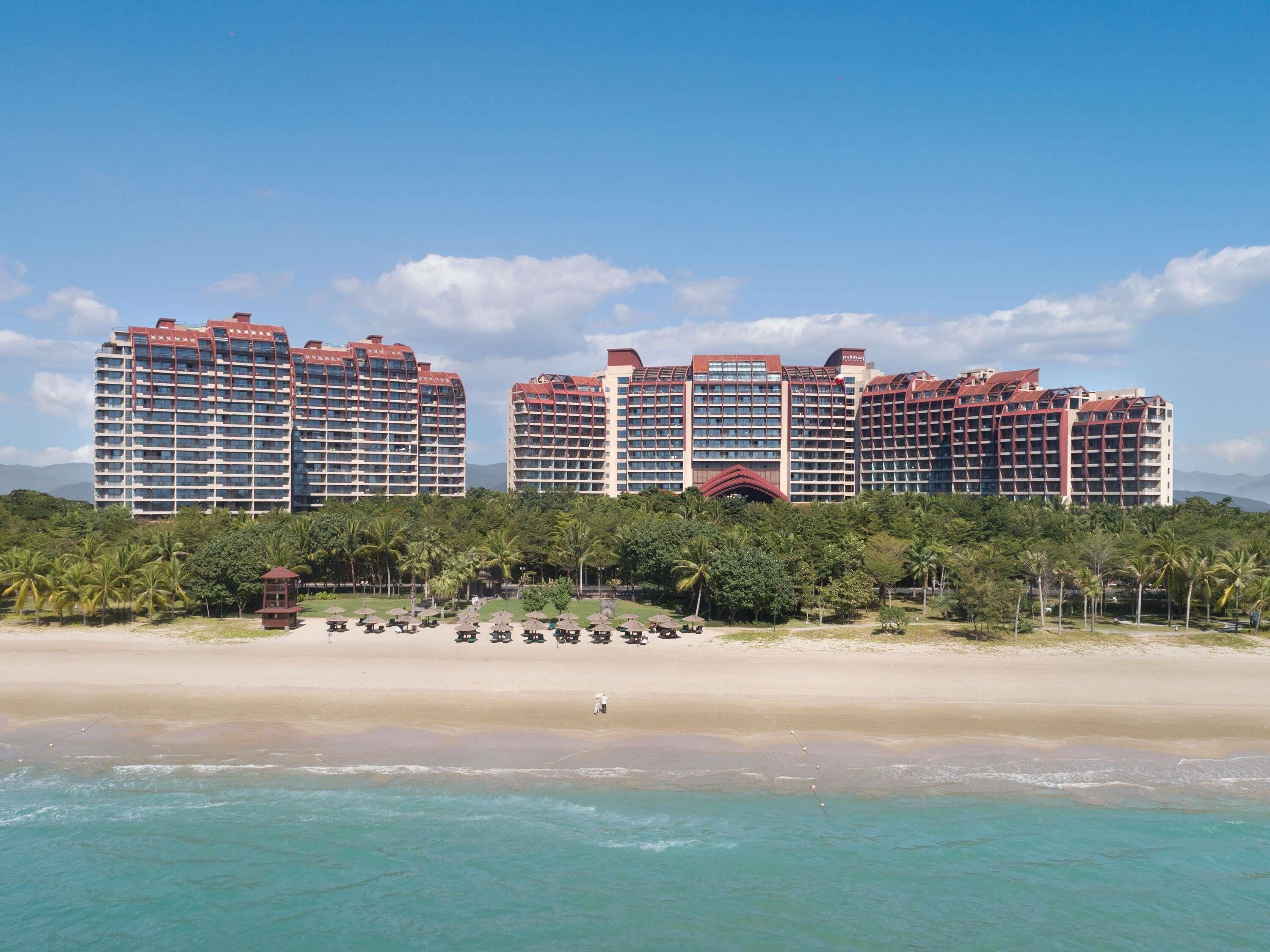 A beachfront hotel with multiple high-rise buildings, a sandy beach, and a clear blue sky.