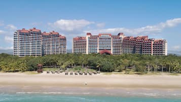 A beachfront hotel with multiple high-rise buildings, a sandy beach, and a clear blue sky.