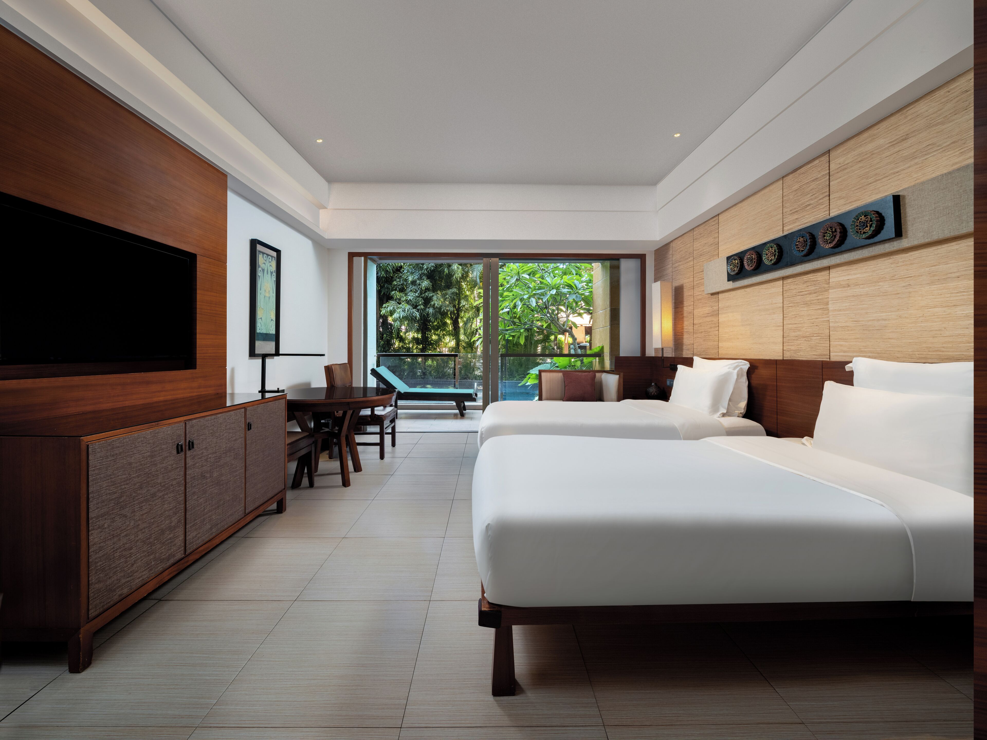 Une chambre d’hôtel moderne dotée d’un grand lit, d’un téléviseur à écran plat, d’une table à manger et offrant une vue sur une piscine.