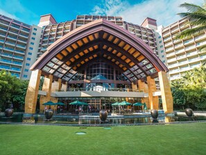 Un hotel con una entrada destacada, un atrium central y un patio circundante con una fuente.