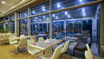 Un restaurante espacioso con techos altos, ventanas grandes y mobiliario moderno.