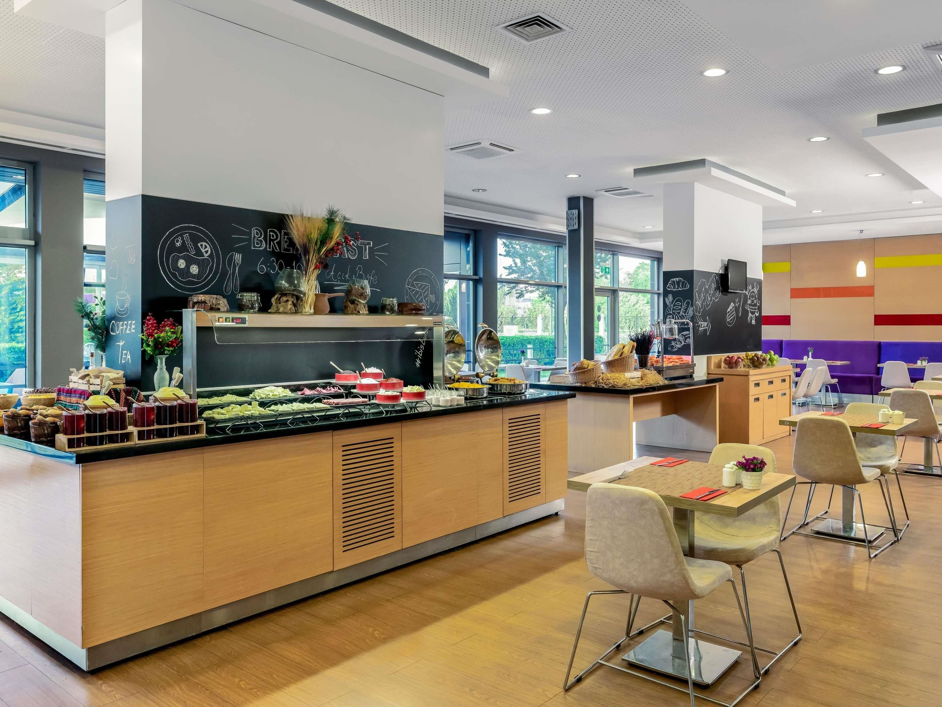 A modern cafe with a breakfast bar, seating area, and large windows.