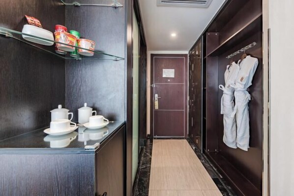 A hotel corridor with a minibar, tea set, and robes on the wall. - Kunming Langwei Hotel (Kunming Railway Station Branch) (Kunming)