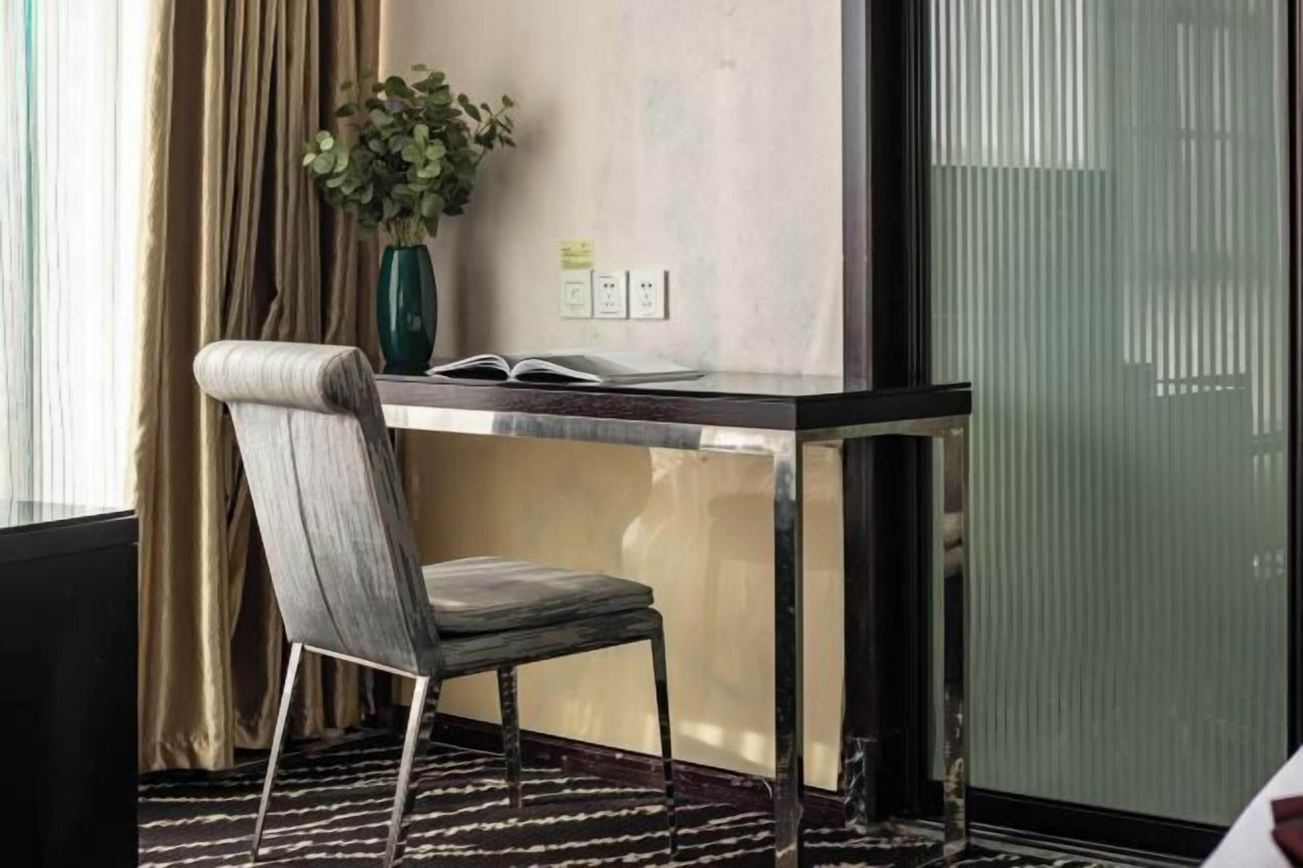 A modern room with a desk, chair, and a potted plant.