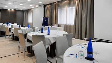 A conference room with round tables, white chairs, and blue water bottles.