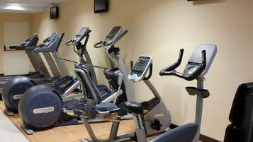 Ein Fitnessraum mit mehreren Trainingsgeräten, darunter Laufbänder und Crosstrainer, die in einer Reihe angeordnet sind.