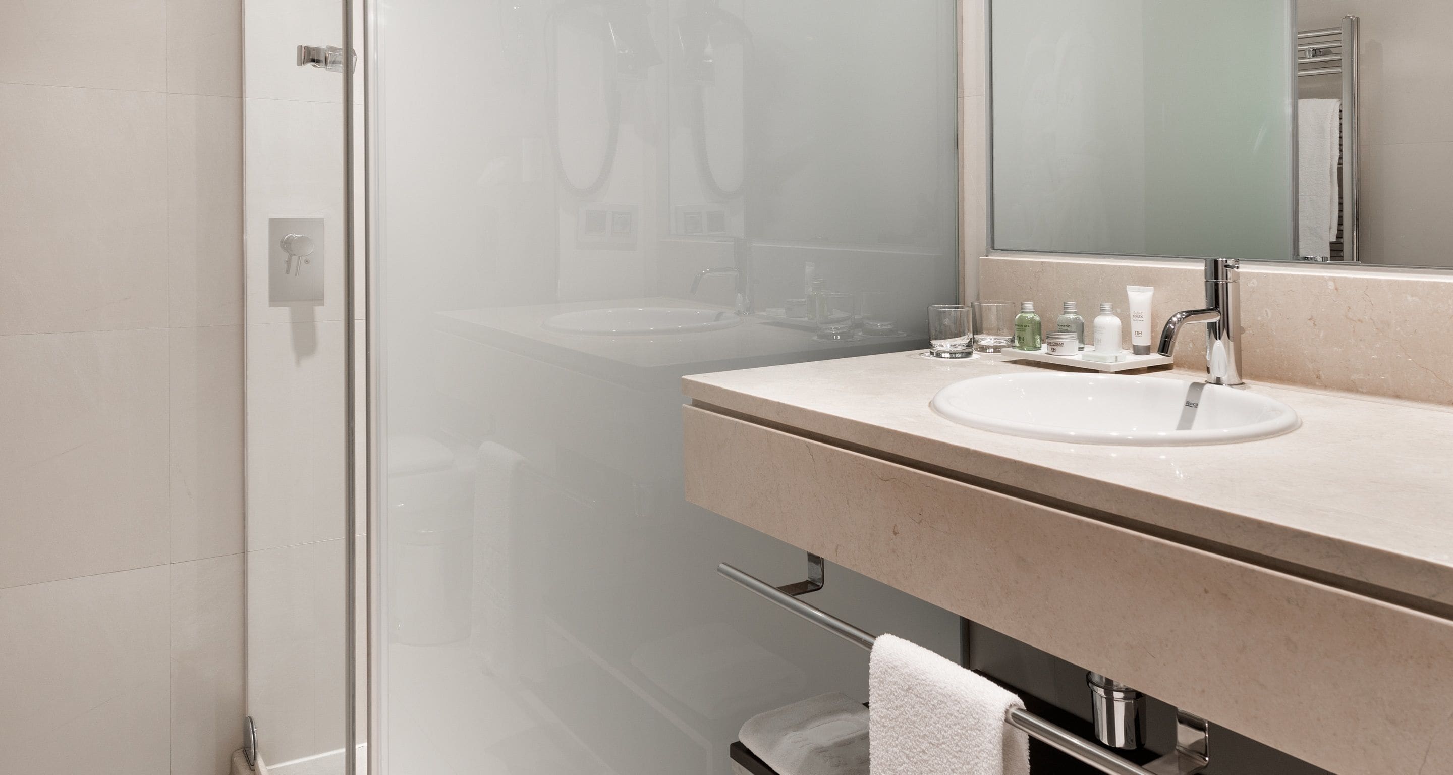 A modern bathroom with a glass shower enclosure, a beige vanity with a sink, and a mirror above the sink.