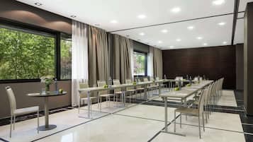 Un salón de conferencias con una larga mesa, sillas y un ventanal con cortinas.