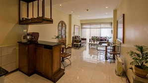 A spacious living area with a kitchen, a dining table, and a sofa. - RQ Hotel Dacarlo (Santiago)