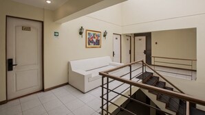 A hotel lobby with a white sofa, a staircase, and a door marked with the number 403. - RQ Hotel Dacarlo (Santiago)