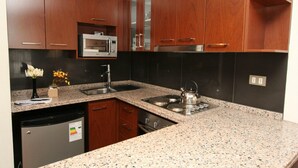 A modern kitchen with granite countertops, stainless steel appliances, and wooden cabinets. - RQ Central (Santiago)