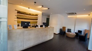 A reception area with a counter, seating, and a wall-mounted display. - RQ Central (Santiago)