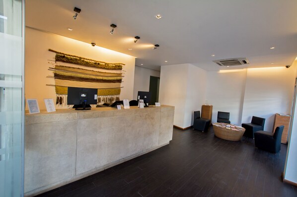 A reception area with a counter, seating, and a wall-mounted display. - RQ Central (Santiago)