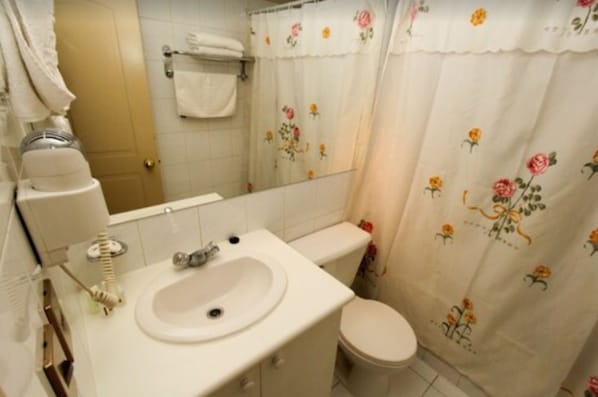 Un bagno con lavandino, wc e tenda da doccia decorata con motivi floreali.