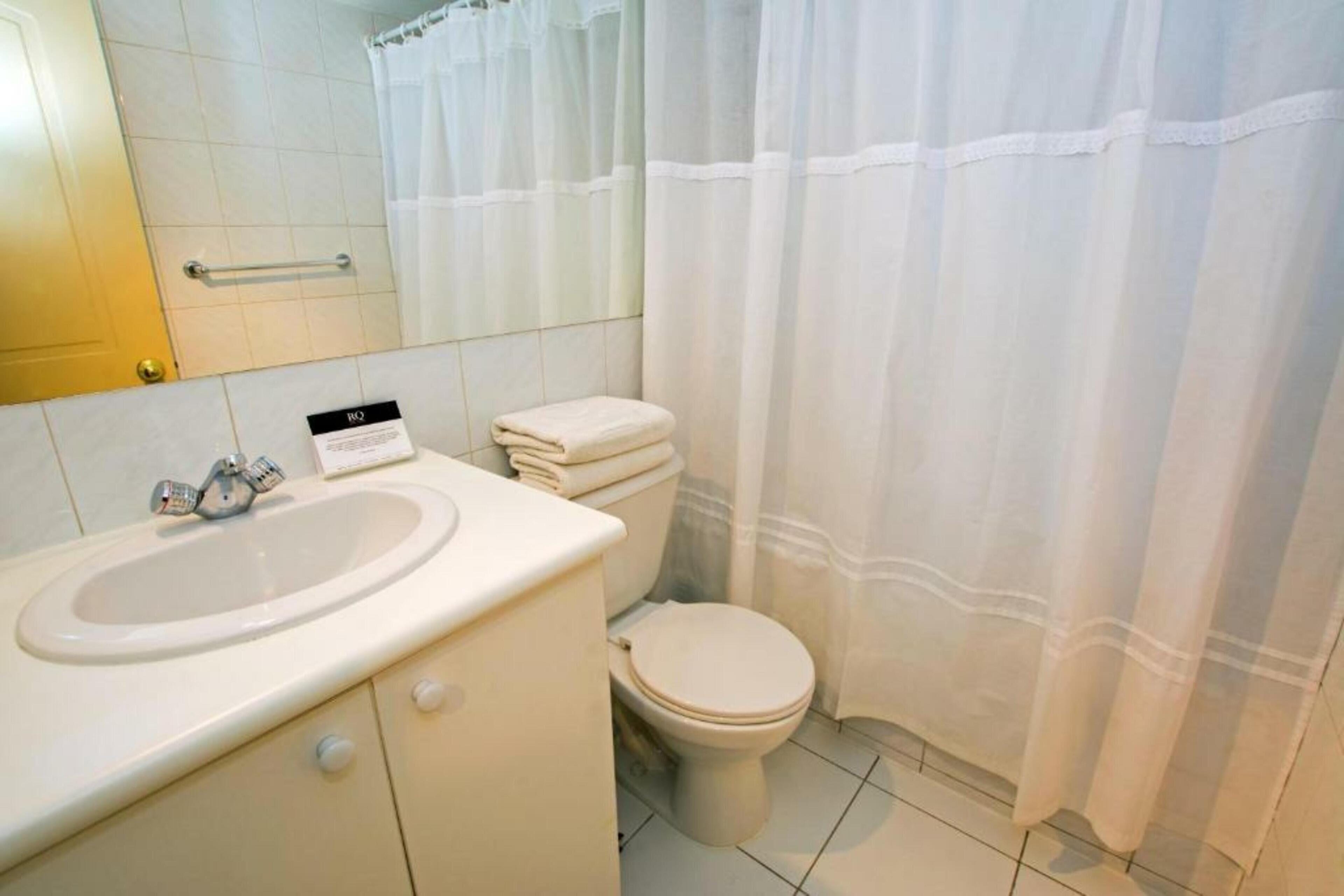 Een badkamer met een wastafel, toilet en douchegordijn.
