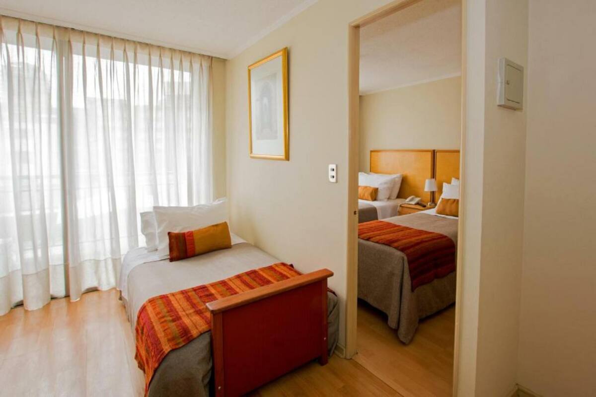 A hotel room with a large bed, a smaller bed, a desk, and a chair.