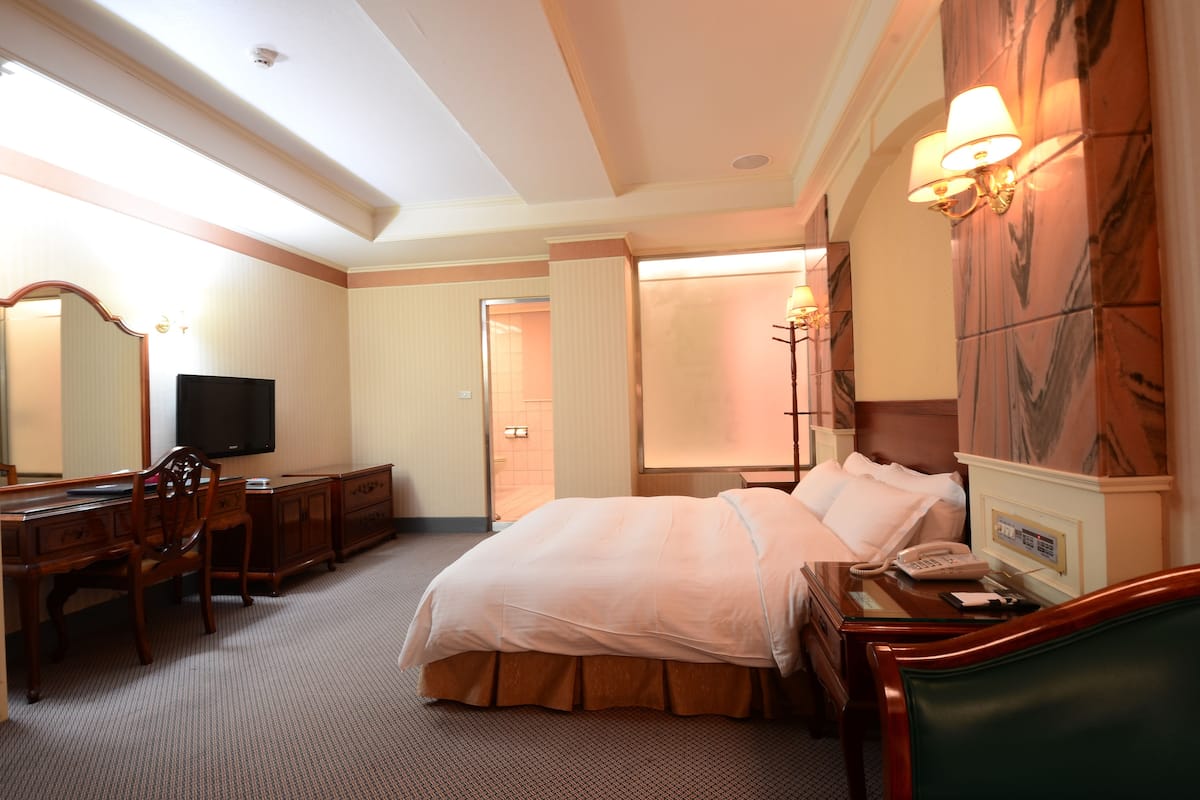 Une chambre d’hôtel équipée d’un lit, d’un bureau, d’une chaise, d’une télévision et d’un téléphone.