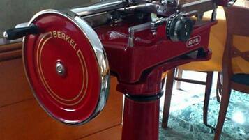 Une machine rouge d’époque, dotée d’un élément circulaire et d’une structure métallique sur le dessus, posée sur un sol carrelé.