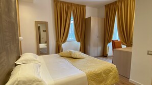 Une chambre d’hôtel avec un lit, un bureau, un miroir et des rideaux.