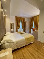 Una habitación de hotel con una cama, un escritorio, un espejo y cortinas.