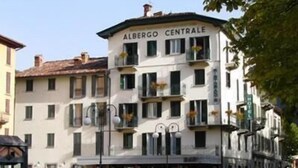 Un bâtiment portant l’inscription « Albergo Centrale », avec plusieurs étages, des balcons et une entrée au niveau du sol.