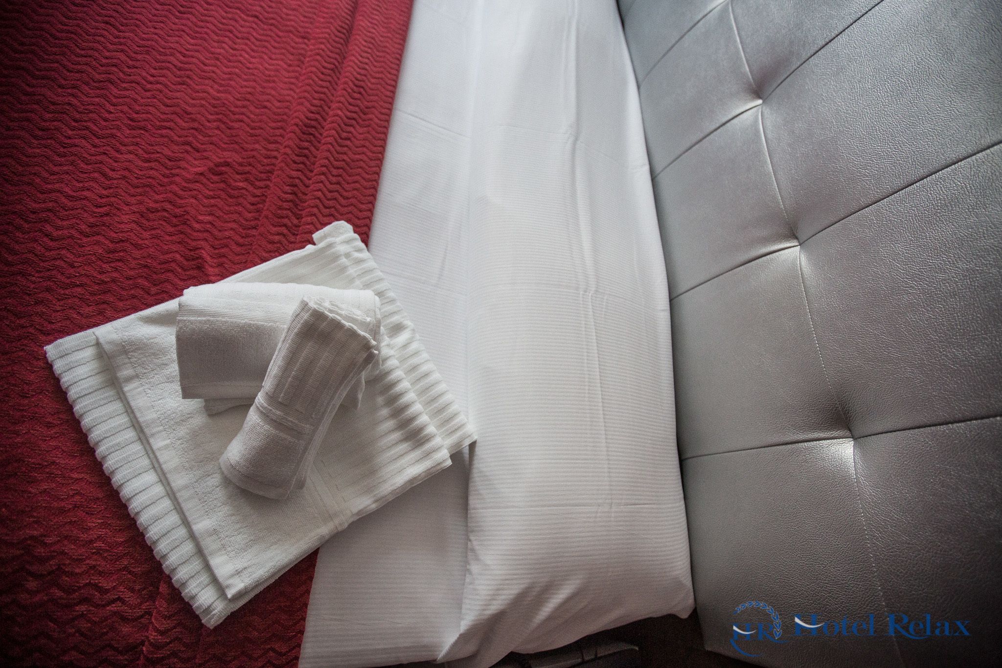 Una cama bien tendida con sábanas blancas y cabecera gris.
