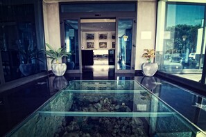 A reception area with a glass aquarium table, potted plants, and framed pictures on the wall. - Hotel Relax (Fiano Romano)