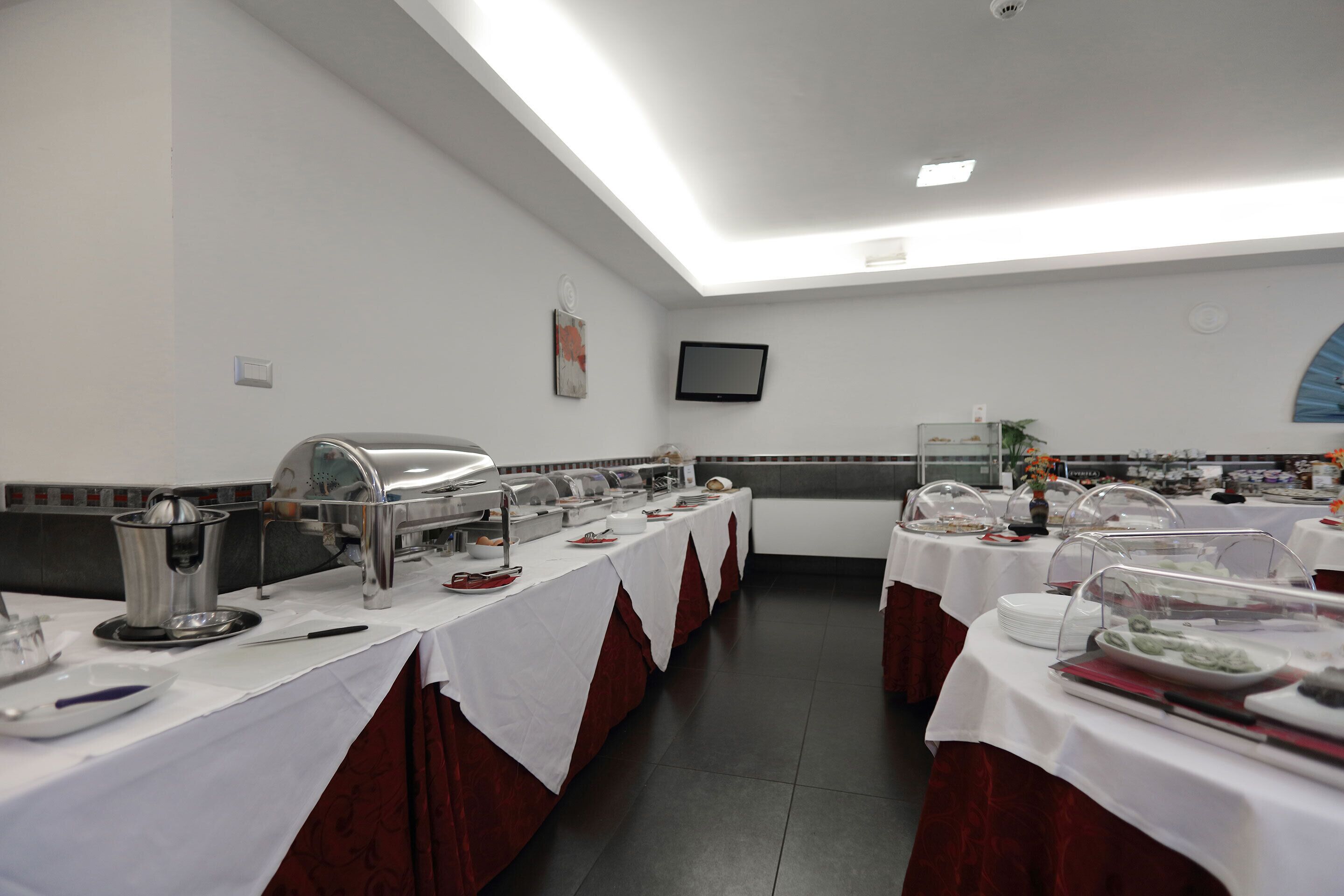 A buffet setup with multiple serving stations, a flat-screen TV, and a tiled backsplash.
