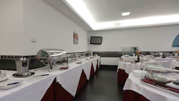 A buffet setup with multiple serving stations, a flat-screen TV, and a tiled backsplash.