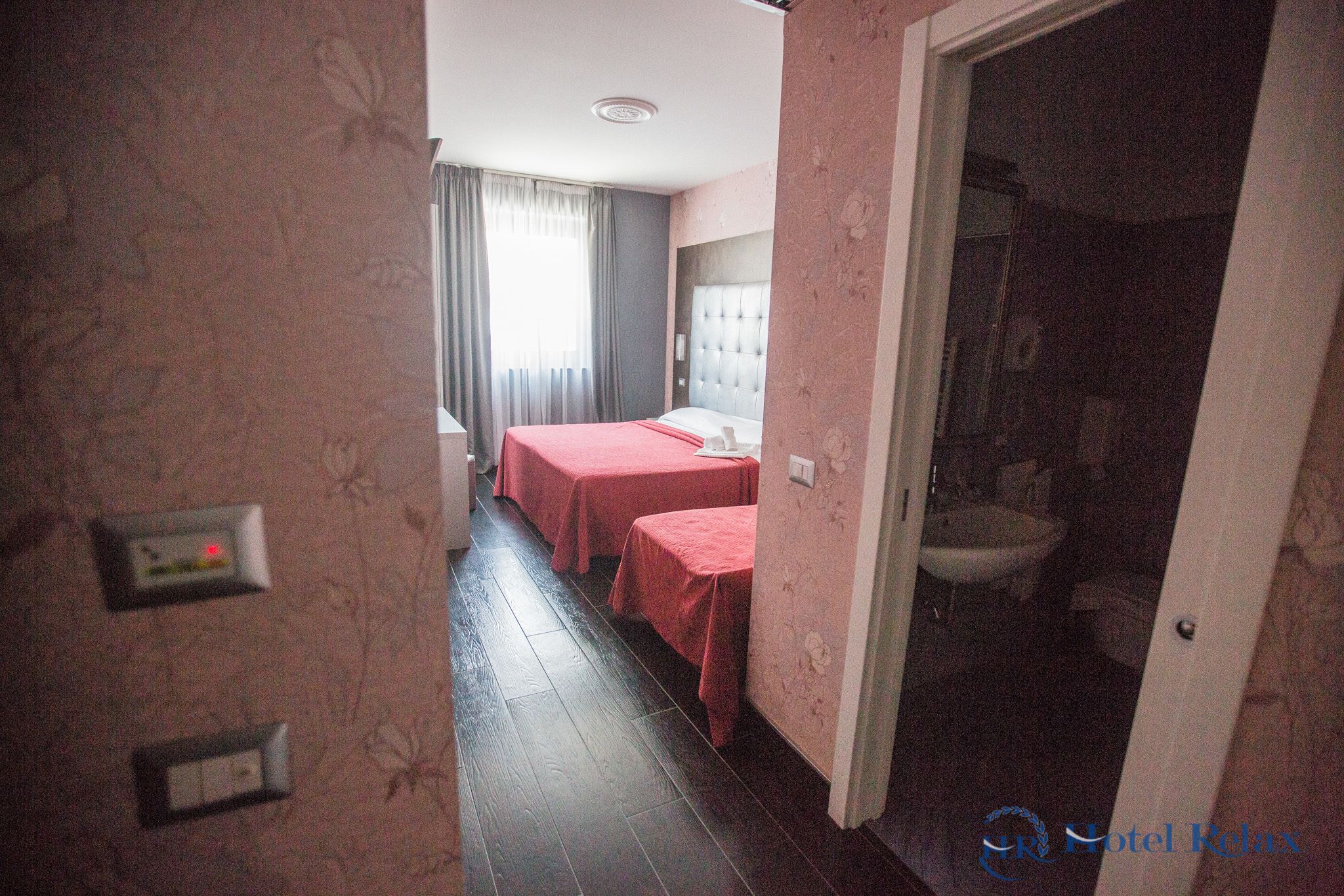 A hotel room with two beds, a bathroom, and a visible toilet.