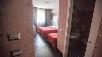 Habitació d'hotel amb dos llits, un bany i un vàter visible.