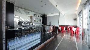 A modern restaurant with a long counter, glass partitions, and red-covered tables. - Hotel Relax (Fiano Romano)