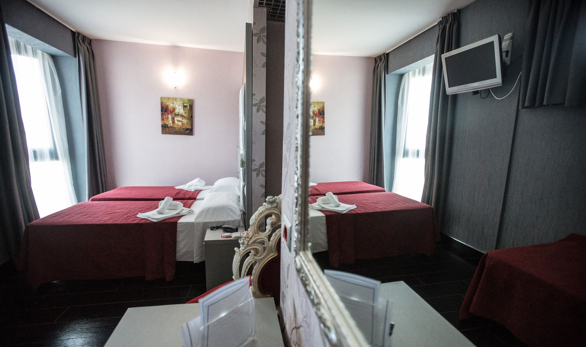 A hotel room with two beds, a TV, and artwork on the walls.
