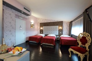 A hotel room with two beds, a desk with a fruit basket, a chair, and a large window with curtains. - Hotel Relax (Fiano Romano)