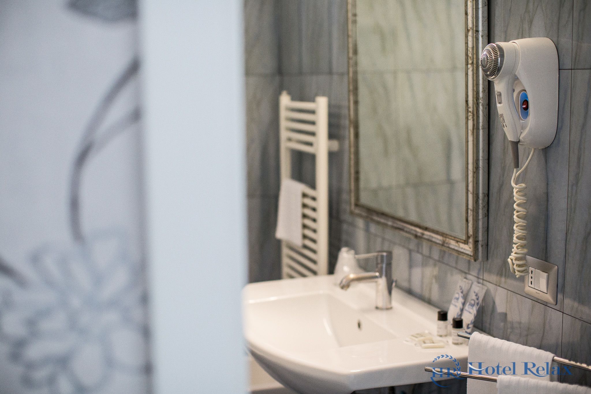 Un baño con lavamanos, espejo y secador de pelo montado en la pared.
